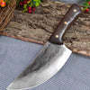 A hand forged stainless steel chef cleaver knife with a wooden handle resting on a cutting board and fabric.