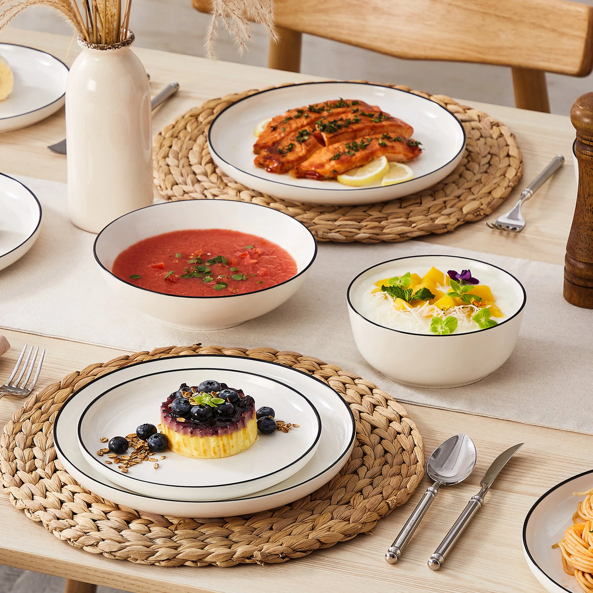 A rustic wooden table set with porcelain dinnerware including plates, bowls, and a baked fish dish.