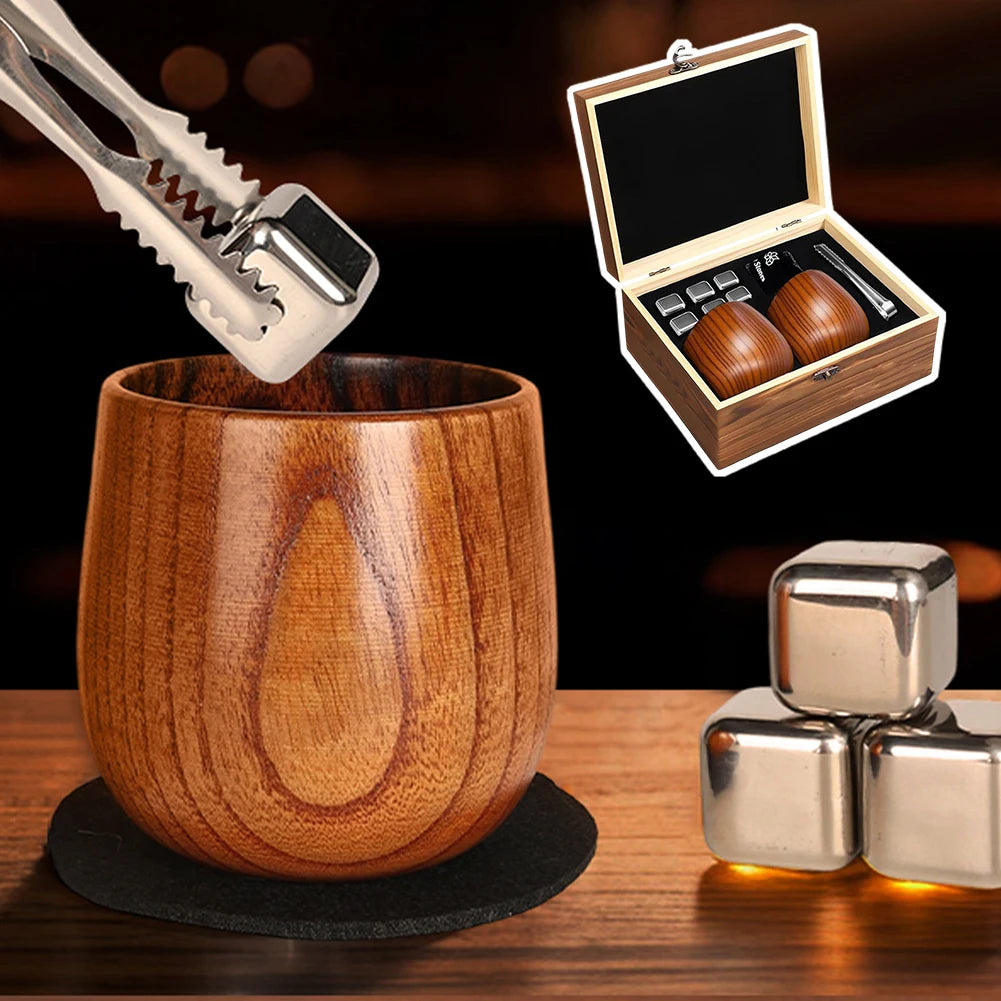 Un ensemble de verres à whisky en bois carbonisé et un outil métallique sont exposés sur une surface en bois.