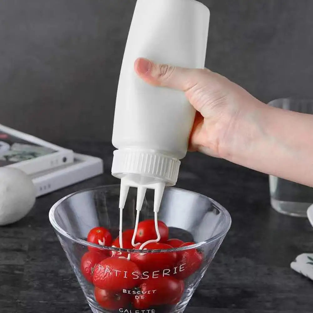 A hand squeezes a white bottle dispenser into a glass bowl filled with red tomatoes.