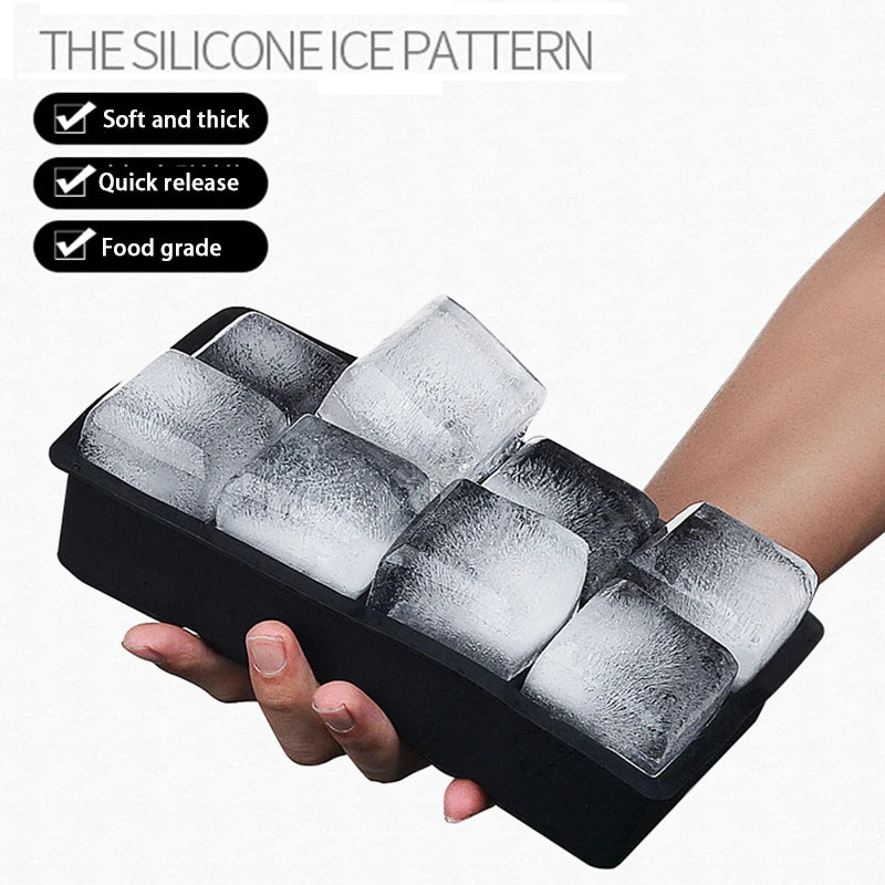 A hand holds a black silicone ice cube tray filled with clear ice cubes, demonstrating the soft and thick, quick release, and