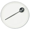 A single stainless steel soup spoon resting on a white plate.