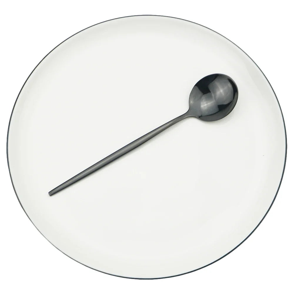 A single stainless steel soup spoon resting on a white plate.