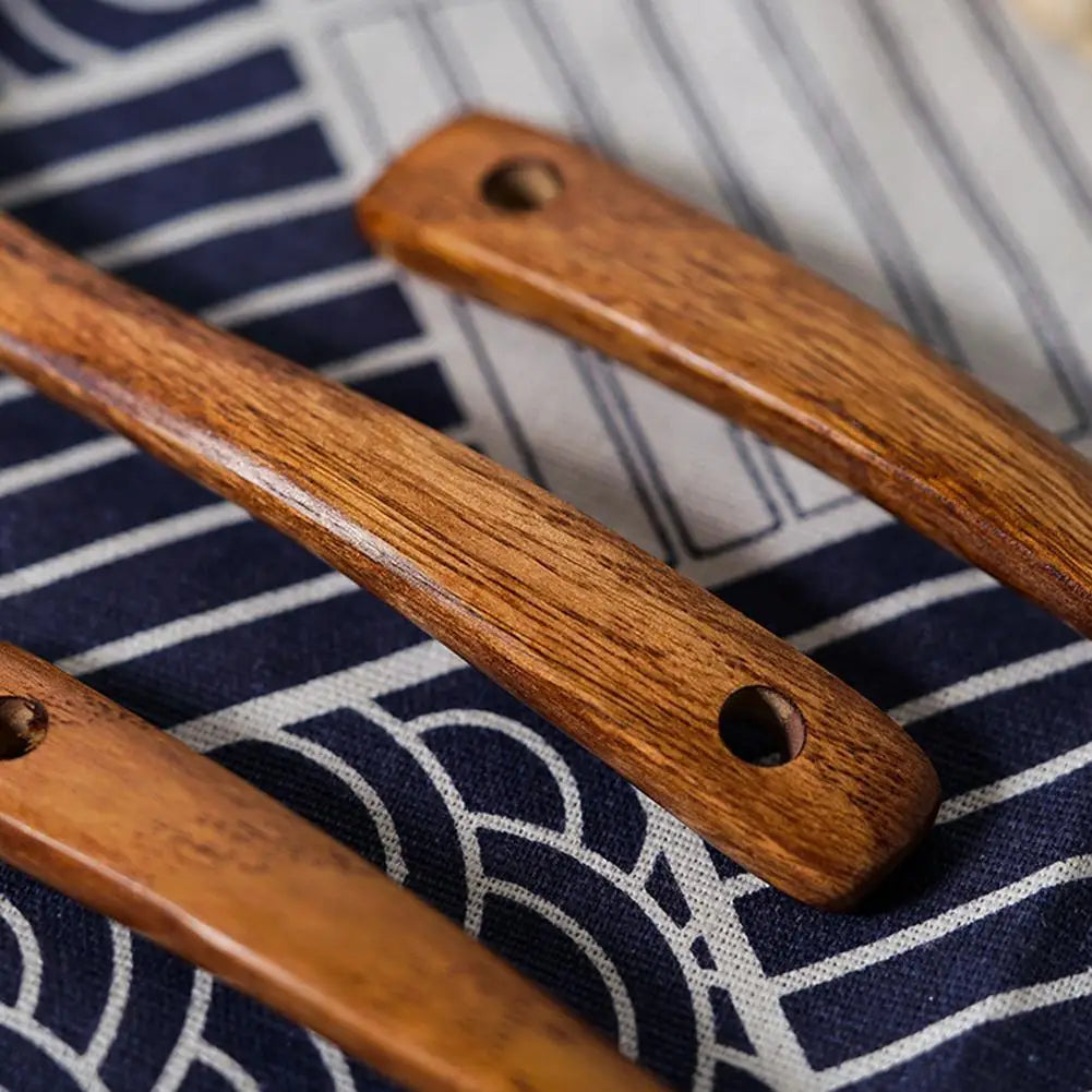 Two natural wooden cooking spoons resting on a dark blue and white striped cloth.