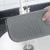 A silicone split drainage anti-splash mat is shown being used to catch water from a faucet into a sink.
