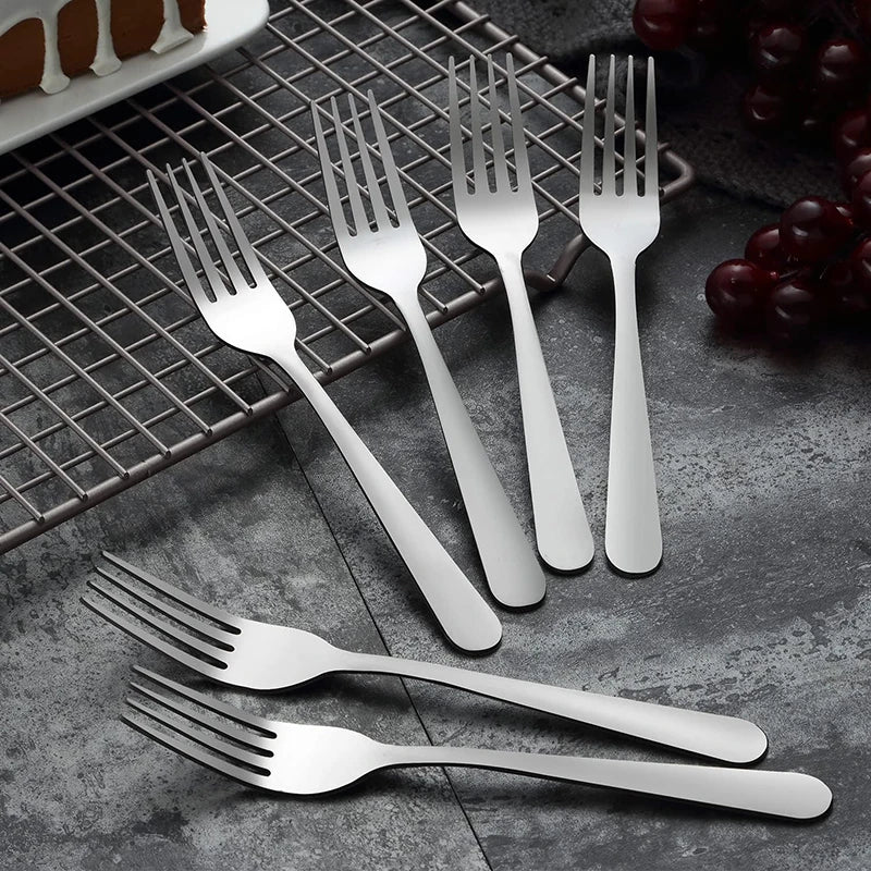 A set of stainless steel dinner forks and a spoon are displayed on a wire rack against a dark gray background.