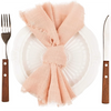 Servilleta de algodón rosa atada en un lazo colocada sobre un plato blanco junto a un tenedor y cuchillo.