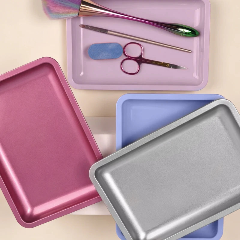 A collection of stainless steel professional nail art and dental tools in various colors and shapes arranged on a light backg