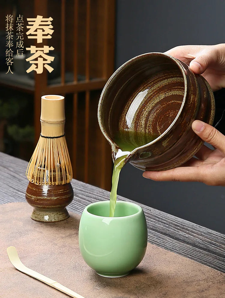 A hand pours green matcha liquid from a dark ceramic bowl into a light green cup.