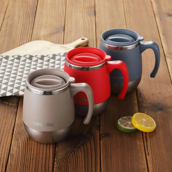 Ein Set von vier vakuumdichten Edelstahl-Kaffeetassen in verschiedenen Farben auf einer Holzoberfläche.