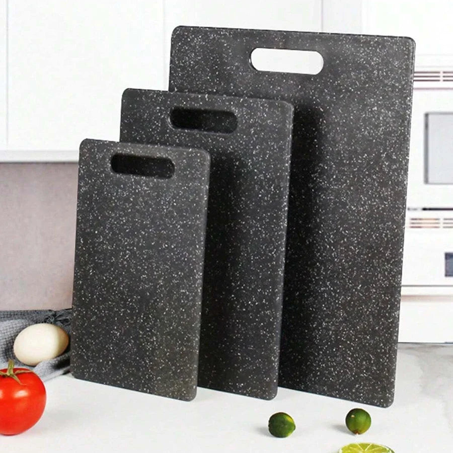 Three black marble texture cutting boards are displayed next to a red tomato and green limes.