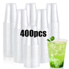 A stack of 400 clear disposable plastic cups and a glass filled with green liquid.
