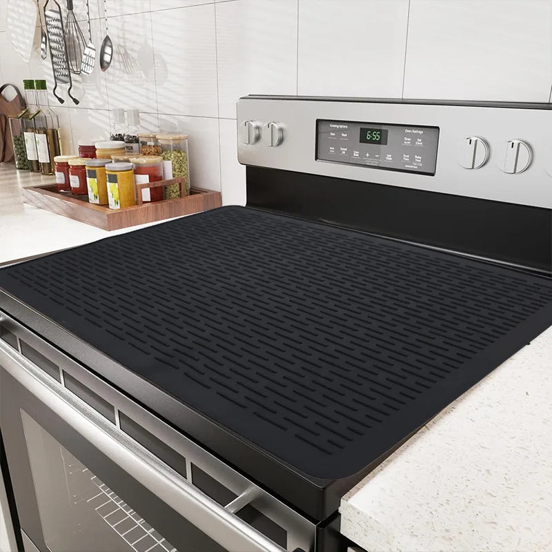 A black silicone induction cooker protector mat is shown in a kitchen setting.
