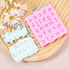 Pink silicone alphabet cake decoration molds with various letters and a white daisy flower