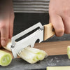 A hand is using a stainless steel peeler with a wooden handle to peel a cucumber or zucchini.