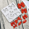 A silicone baking mold set featuring various decorative bows and flowers in a matte white color.