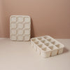 A white silicone food tray with multiple compartments is displayed on a beige surface.