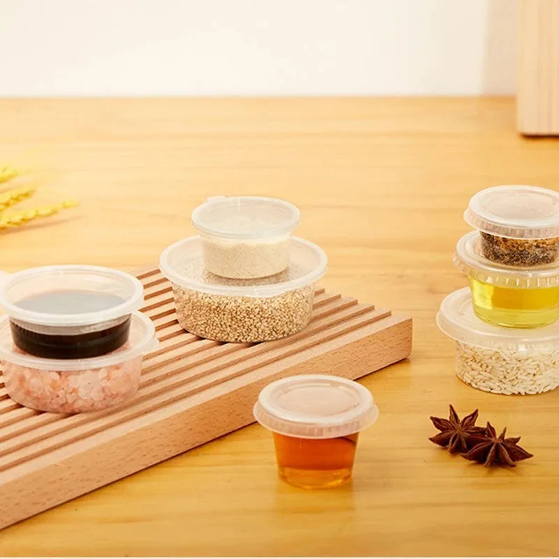 A wooden tray holds several clear disposable sauce cups filled with various colored sauces and spices on a light wood surface