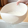 A hand is pouring liquid through a white multi-purpose kitchen strainer or sieve into a sink.