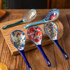 A set of four ceramic ladles with floral patterns arranged on a wooden cutting board.