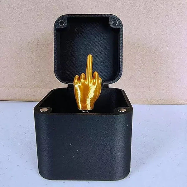 A black gift box with an open lid displaying a golden hand making the middle finger gesture.