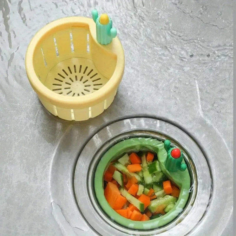 Yellow plastic sink drain strainer with green cactus-shaped drainer tool.