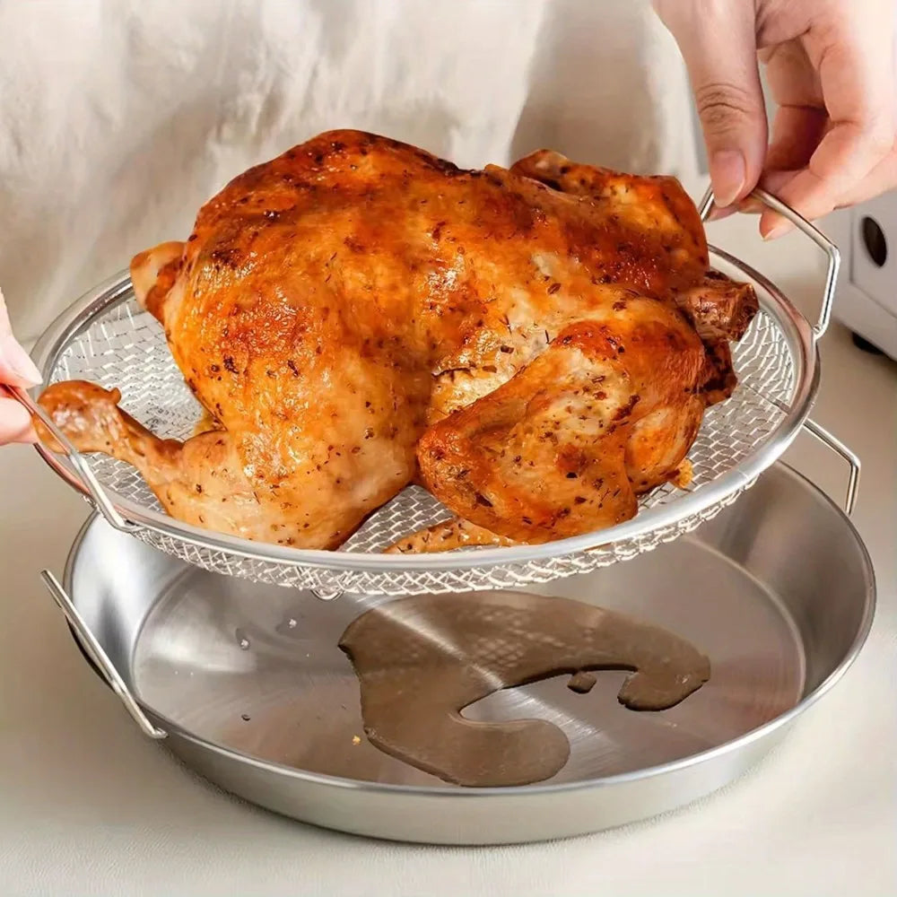 A hand places a roasted chicken onto a heavy duty stainless steel frying rack with an oil draining basket.