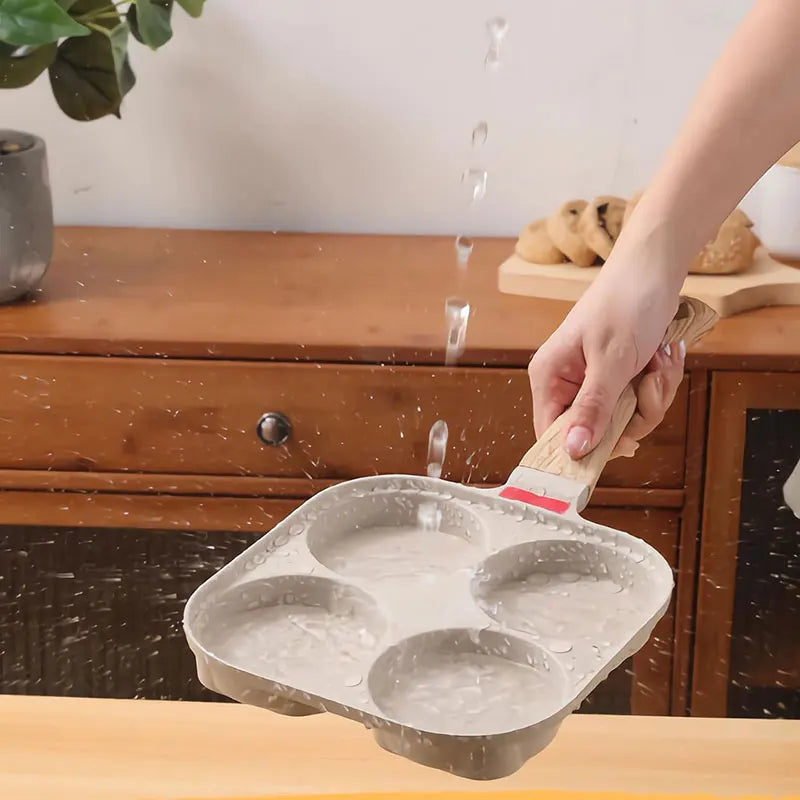 A hand is pouring liquid into a nonstick omelette pan, demonstrating the product.