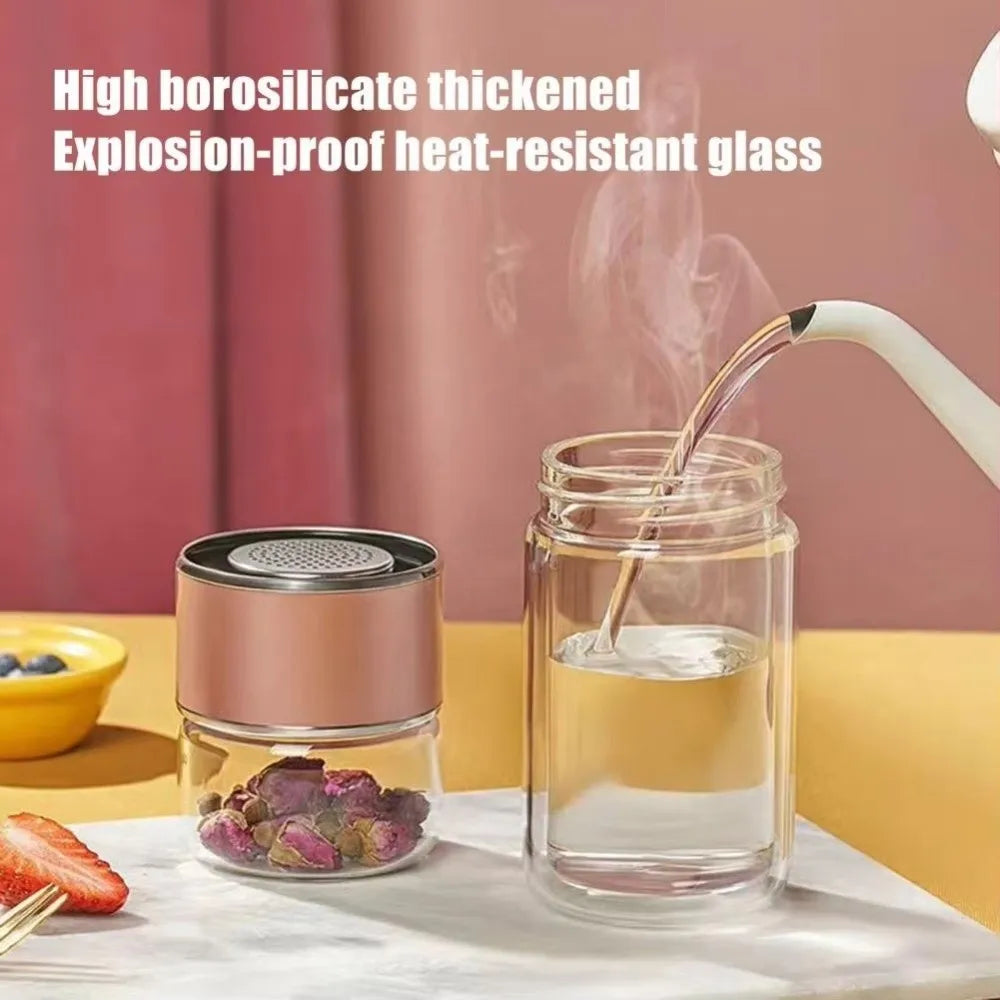 A clear glass tea infuser jar filled with water, next to a pink and silver lid and some dried herbs.
