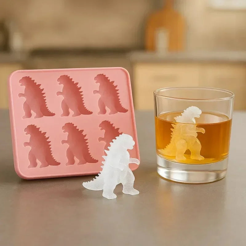 A pink silicone dinosaur ice cube tray set with a dinosaur shaped ice cube visible next to a glass.