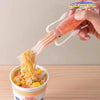 A hand is using a funny squid cuttlefish shaped fork to lift noodles from a bowl of food.