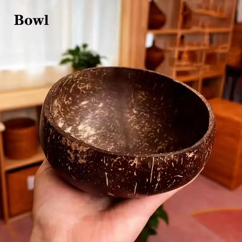 A hand holds a dark brown natural coconut shell serving bowl.