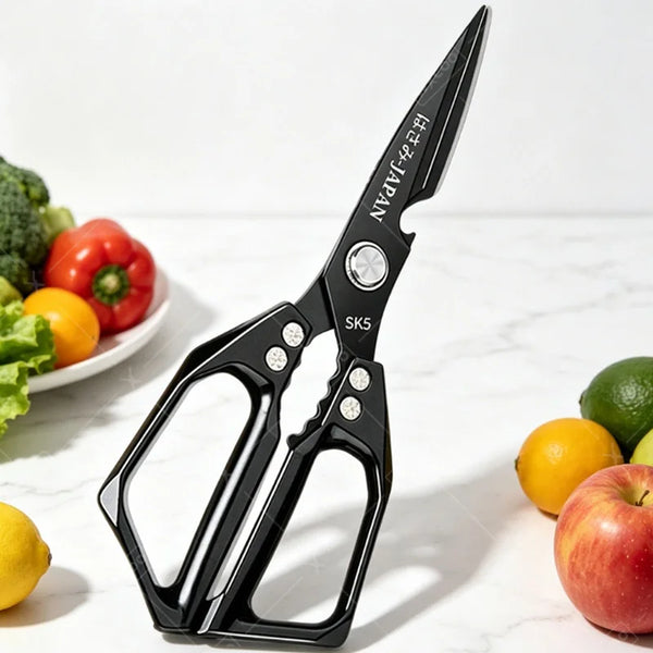 Schwarze, robuste Küchenschere mit silbernen Akzenten auf weißem Marmor neben frischen Produkten.