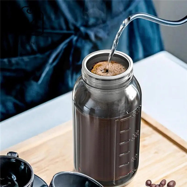 Ein Fluss kaltgebrühter Kaffee wird in ein Einmachglas auf einer Holzoberfläche gegossen.
