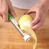 Mains utilisant un éplucheur et un noyau de fruit en acier inoxydable pour retirer la peau d'un citron.