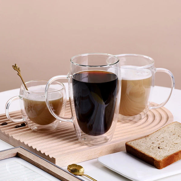 Set klare, hitzebeständige, doppelwandige Gläser gefüllt mit dunkem Kaffee und hellem Tee auf einem Holzbrett.