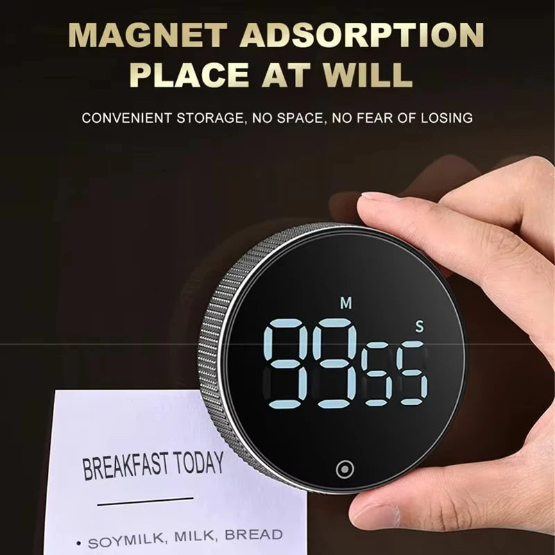 A hand holds a magnetic kitchen timer with a digital display showing 99:55, next to a list of breakfast items.