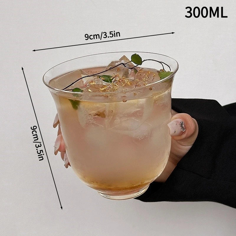 A hand holds a 300ml glass tumbler filled with iced beverage and mint leaves.