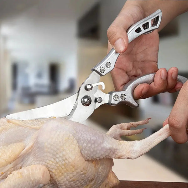 Eine Hand benutzt professionelle Edelstahl-Küchenschere, um einen Hähnchenfuß zu schneiden.