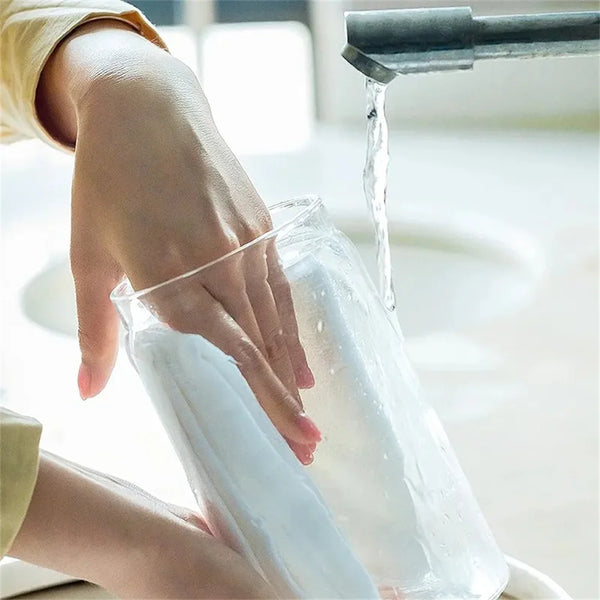 Eine Hand gießt eine klare Flüssigkeit in ein vakuumversiegeltes Glas-Lebensmittelgefäß.
