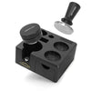 A black precision coffee tamping station with a removable aluminum puck and a separate tamper.