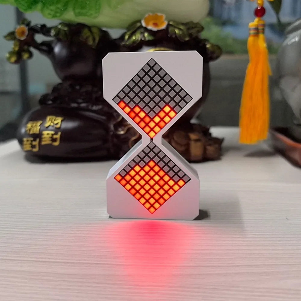 A white LED digital hourglass timer with a red light glow, shaped like an hourglass, resting on a white surface.
