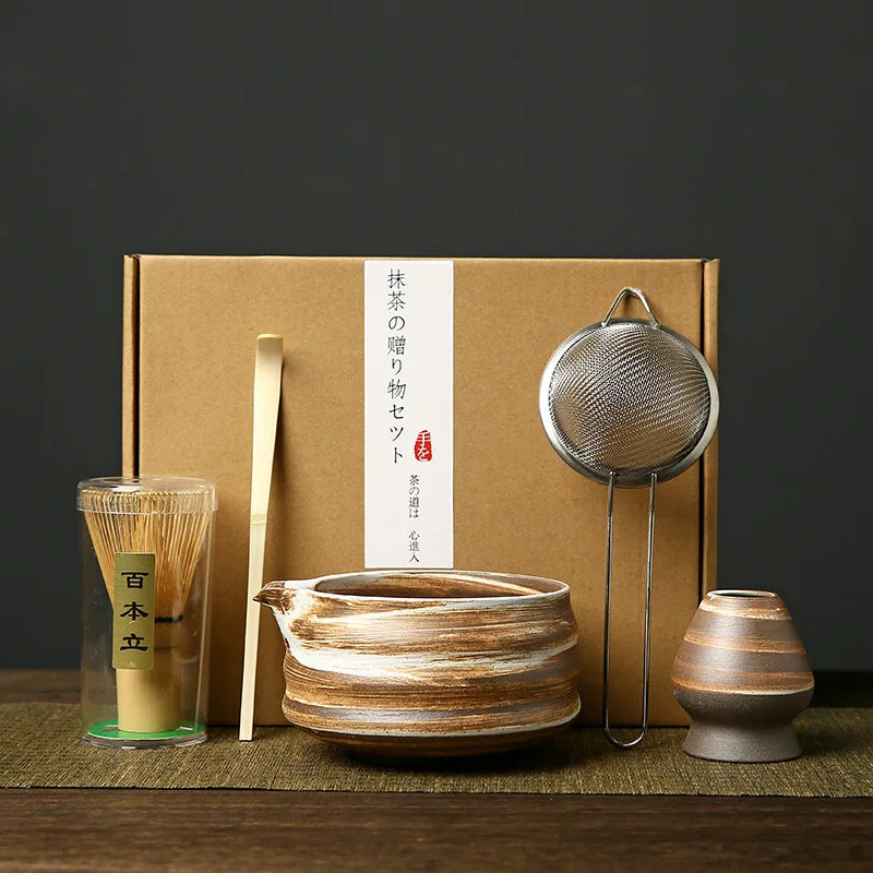 A set of Japanese matcha whisks and related tools packaged in a brown box, displayed on a wooden surface.