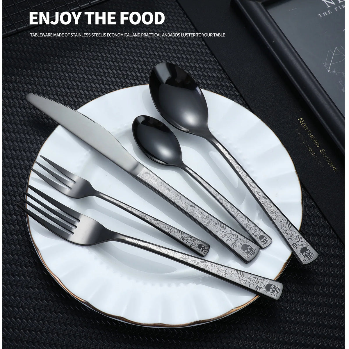 A set of stainless steel cutlery including a knife, fork, spoon, and soup spoon displayed on a white plate.