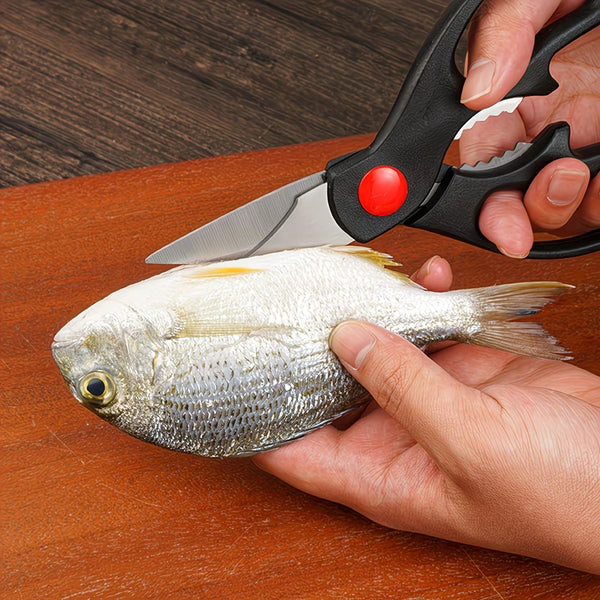 Eine Hand benutzt eine Edelstahl-Küchenschere, um einen Fisch auf einer Holzoberfläche zu schneiden.