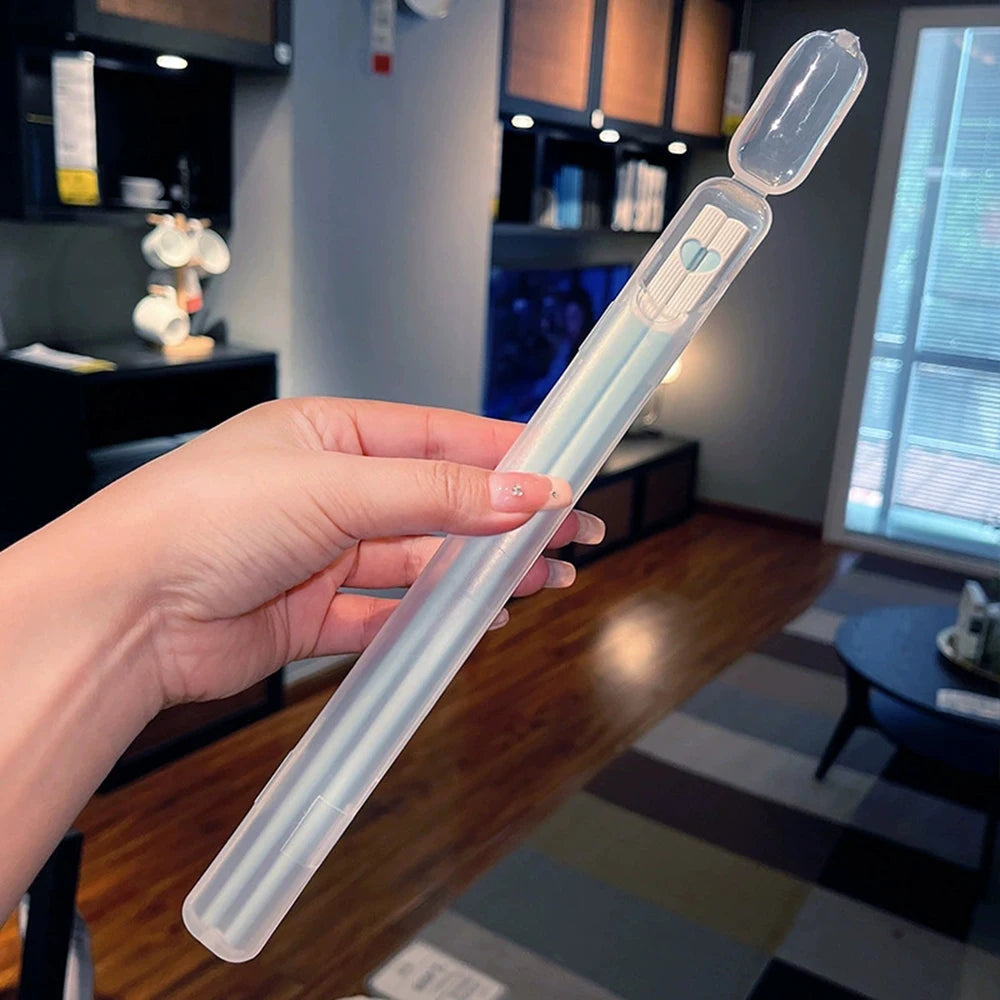 A hand holds a clear plastic chopsticks set with light blue accents against a blurred indoor background.