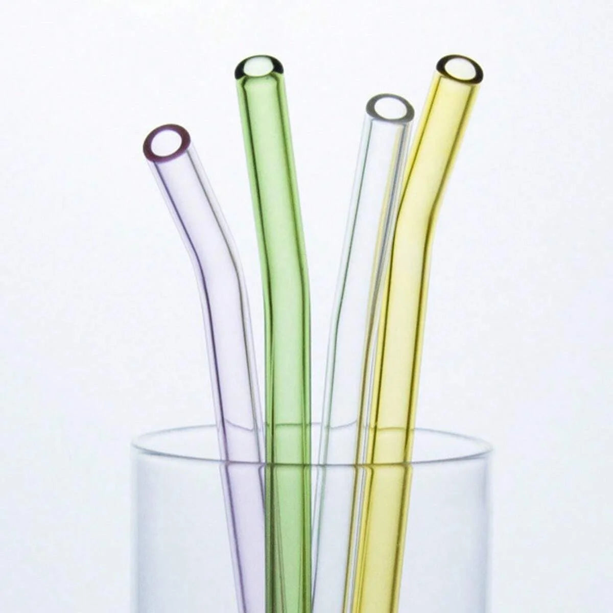 A collection of five reusable glass smoothie straws in various shades of green and yellow are shown in a clear glass containe