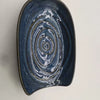 A dark blue ceramic cutlery holder with concentric swirling patterns and a gold rim.