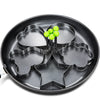 A black stainless steel fried egg mold with multiple shapes and a cluster of green eggs.