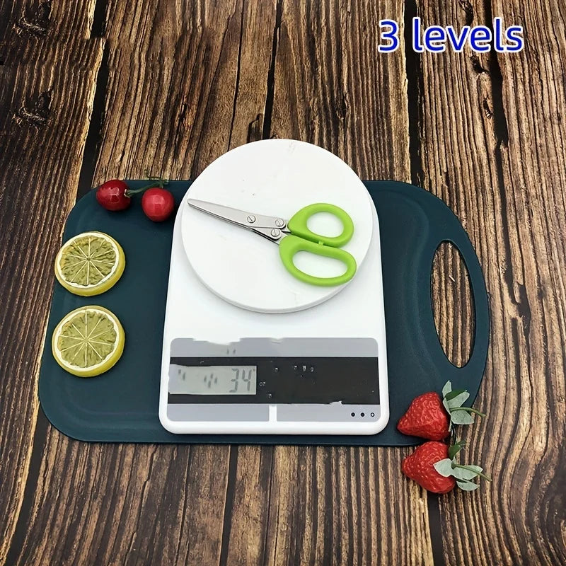 A white digital scale with a green scissor rests on a dark green cutting board, surrounded by fresh citrus and berries.